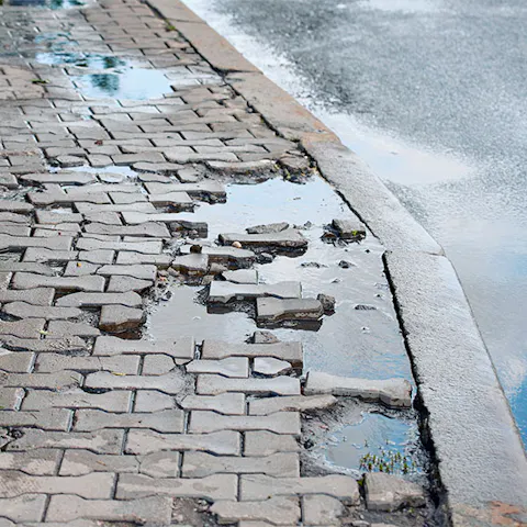 Broken, uneven brick sidewalk creating a trip hazard