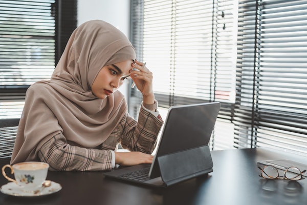 Sad woman in hijab at work