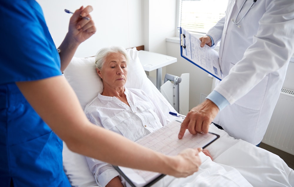Woman in hospital bed listening to doctors