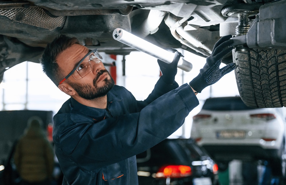 Mechanic looking at underside of car