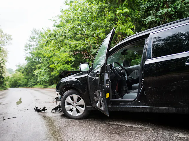 Damaged black SUV with its door open after an accident