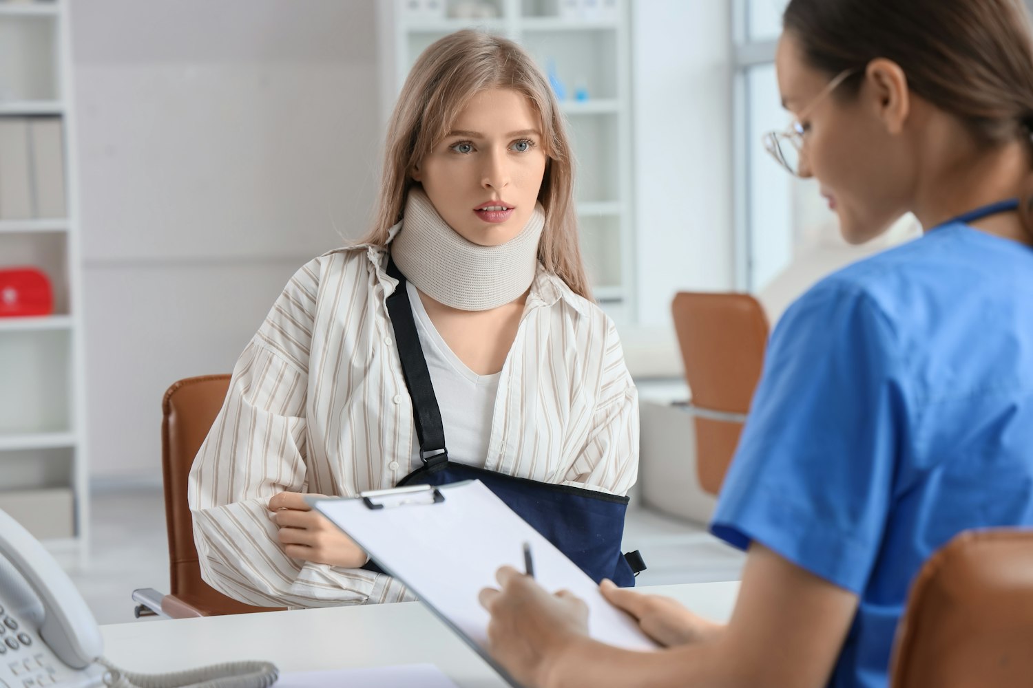 Woman in neck brace speaking to physician