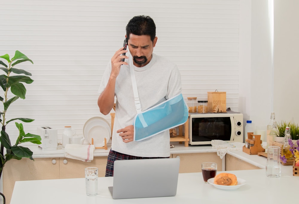 man in sling on the phone