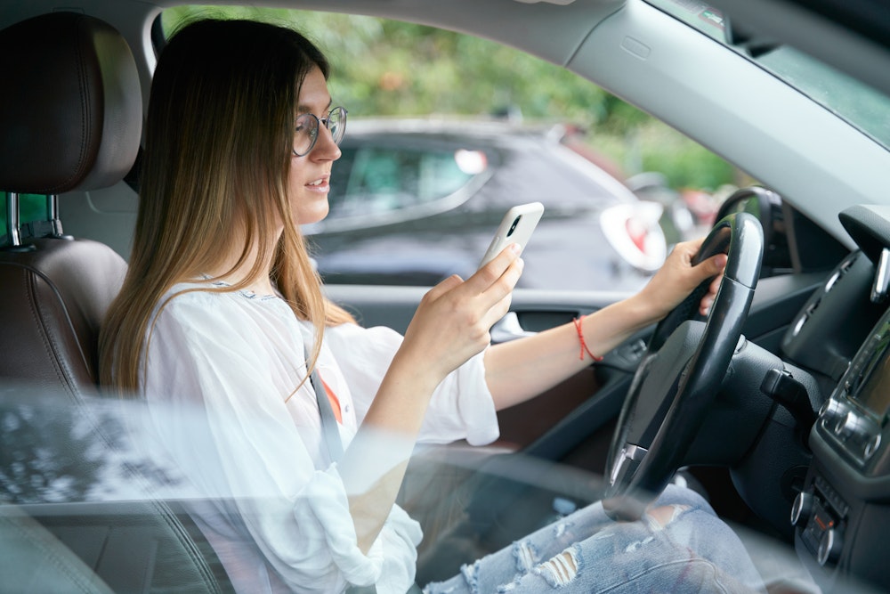 Woman looking at her phone while driving
