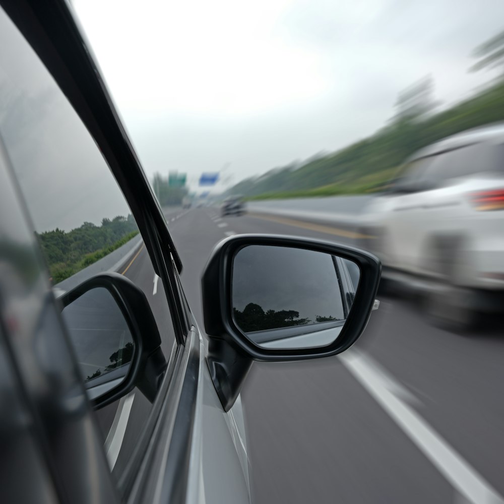 Close-up of a car's side mirror while speeding on a highway
