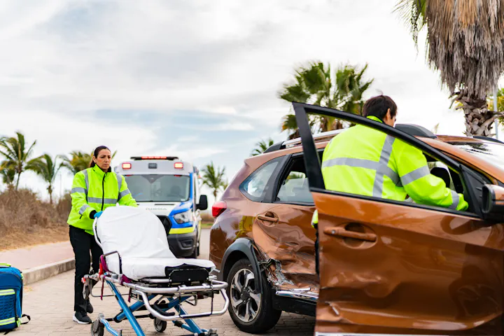 Emergency responders with a stretcher at a car crash scene