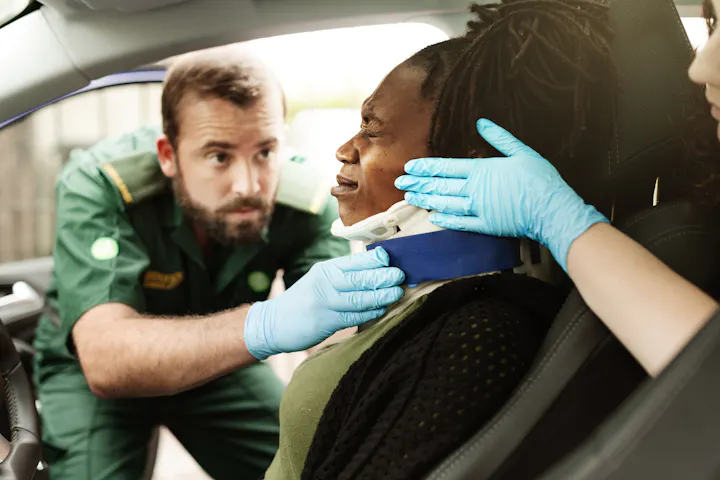 Paramedic fitting a neck brace on a driver after a crash