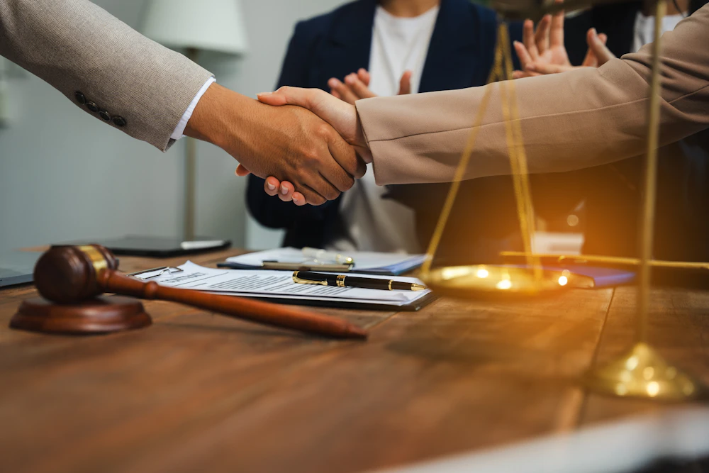 Two people shaking hands over a desk