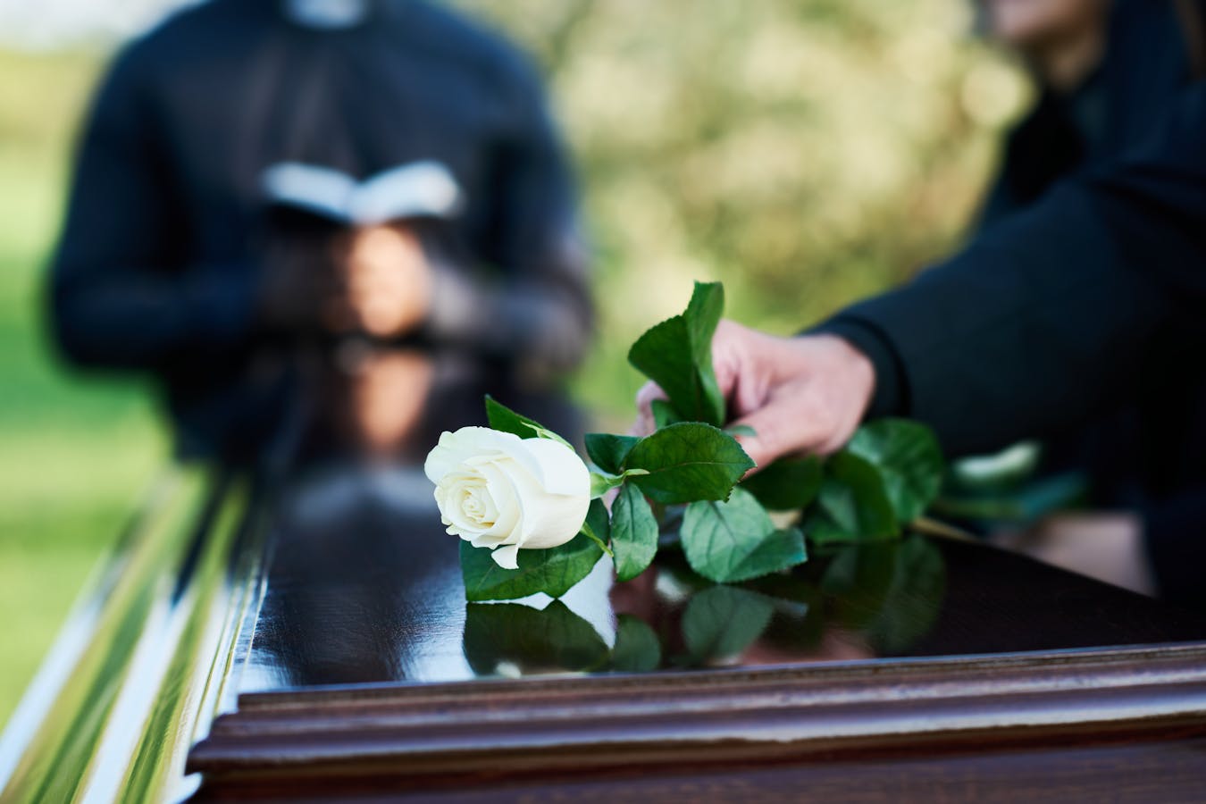 hand and flowers on casket