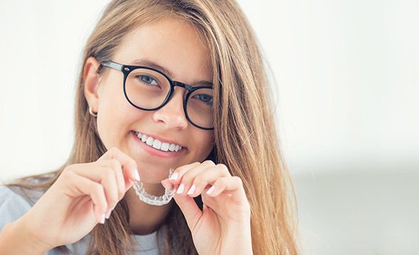 Teenage girl holding Invisalign tray