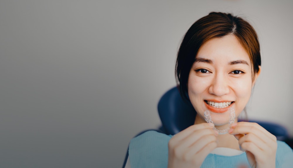 Smiling woman holding Invisalign tray