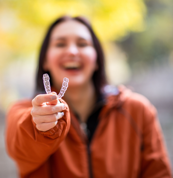 Laughing woman holding Invisalign tray
