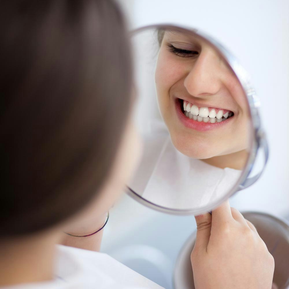 Girl looking at teeth in the mirror