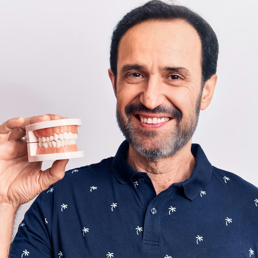 Smiling man holding model teeth