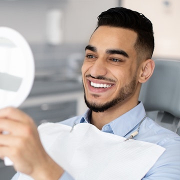 A man examining his new smile in the mirror