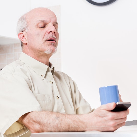 an older man holding his phone at arms length to read it