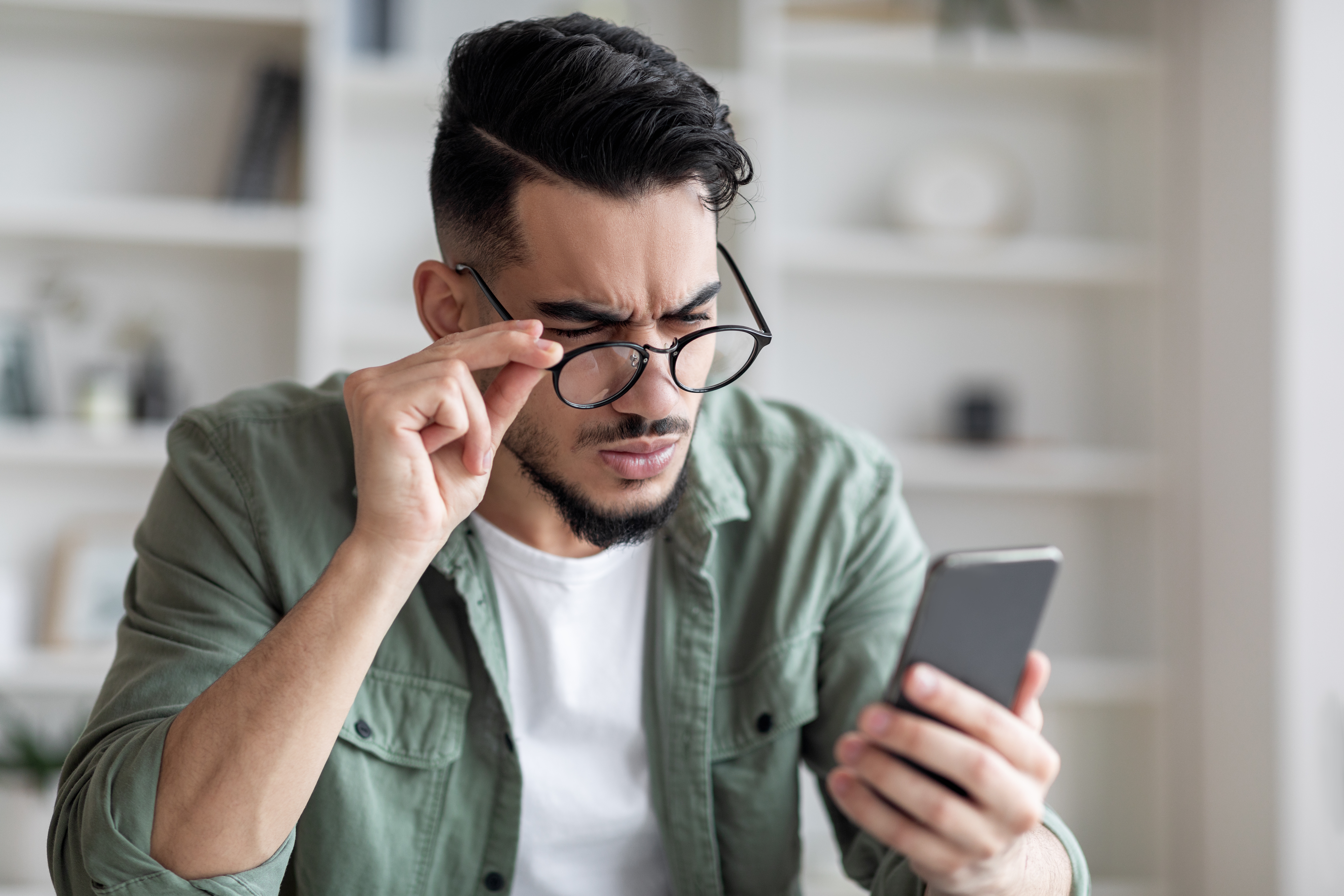 Young man struggling to see even while wearing glasses
