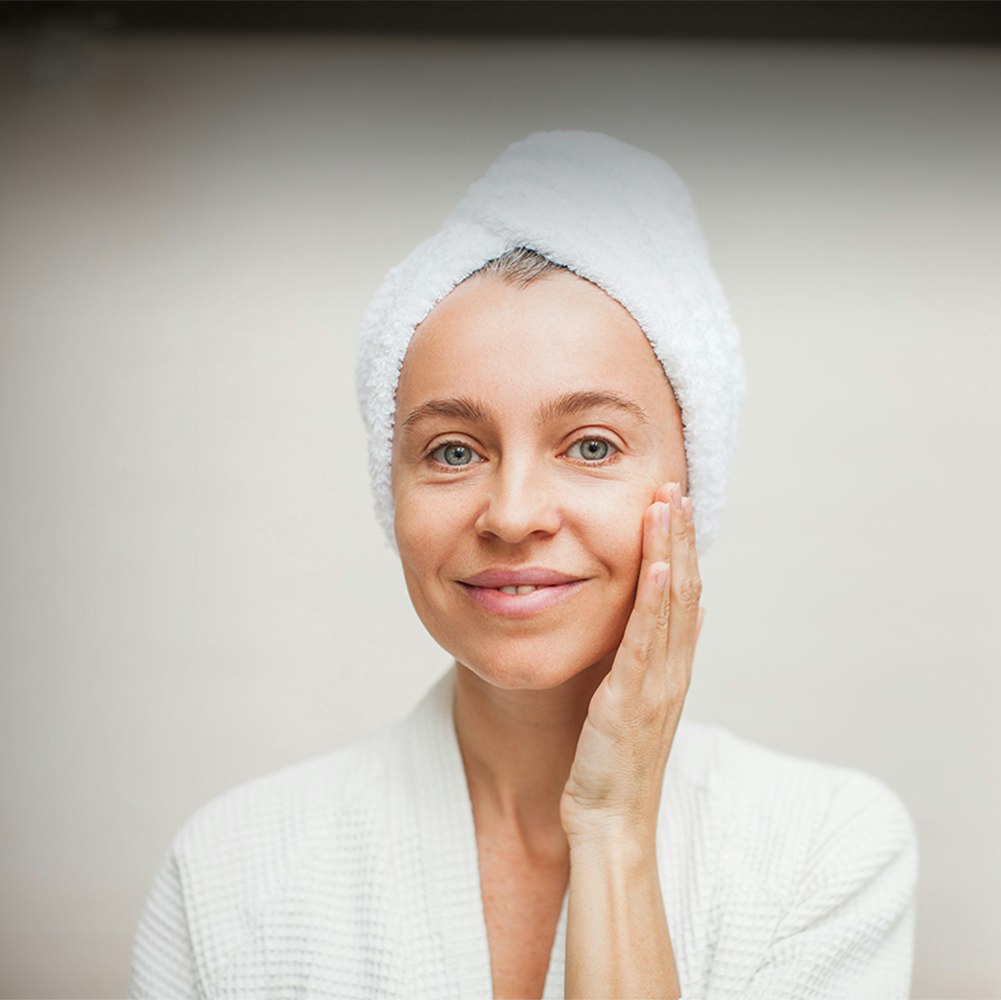 middle-aged woman looking at herself after spa treatment and she has very few wrinkles