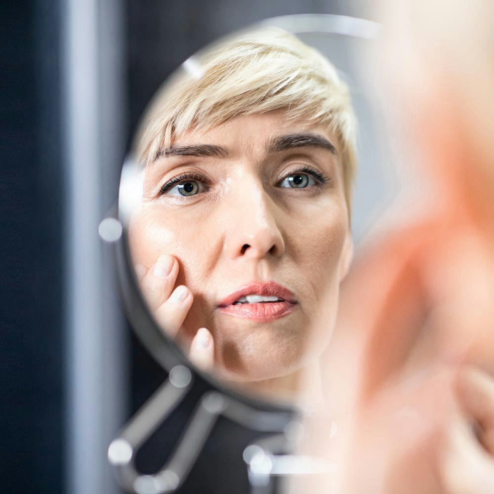 Older woman looking at face in mirror
