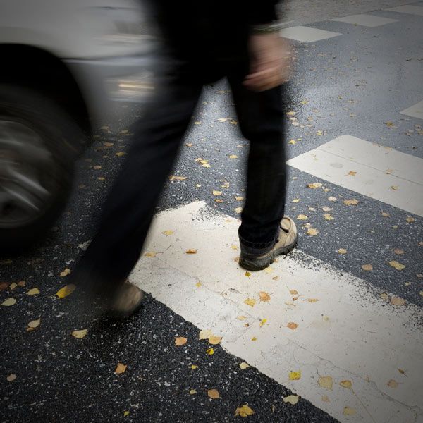 Pedestrian walking across the street with car coming
