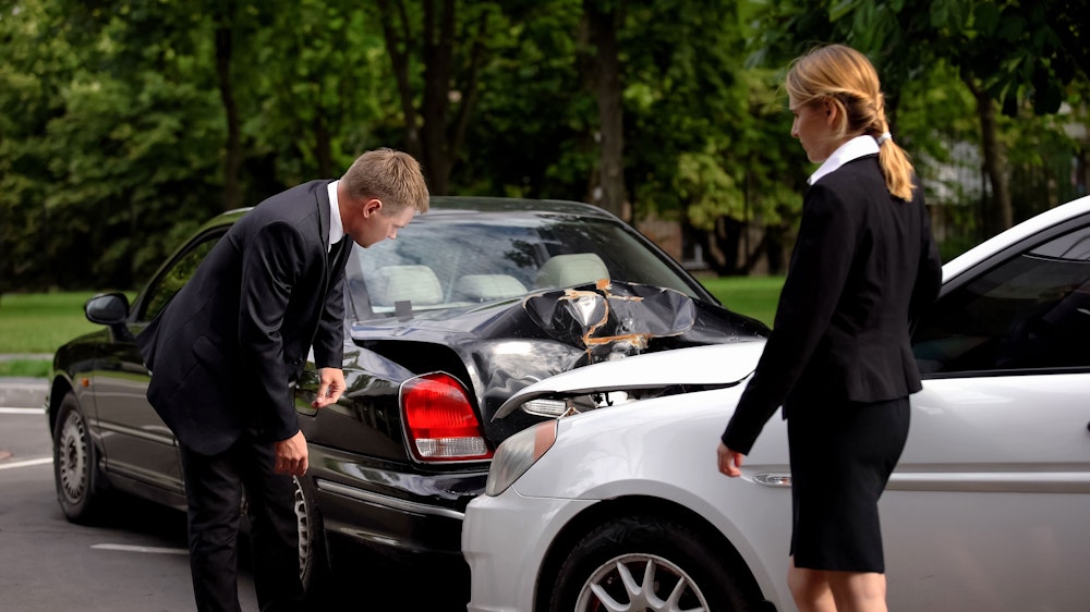 Two people viewing the damage from a car accident
