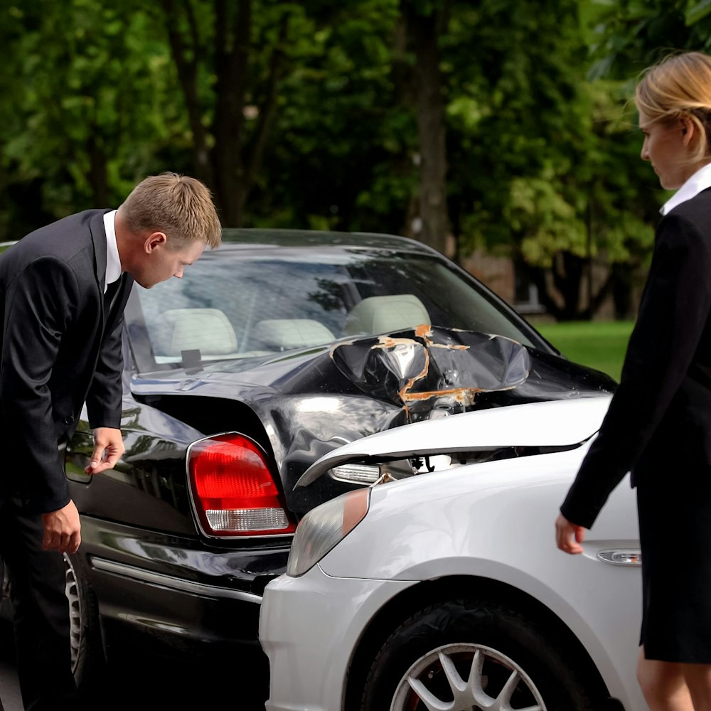 Two people viewing the damage from a car accident