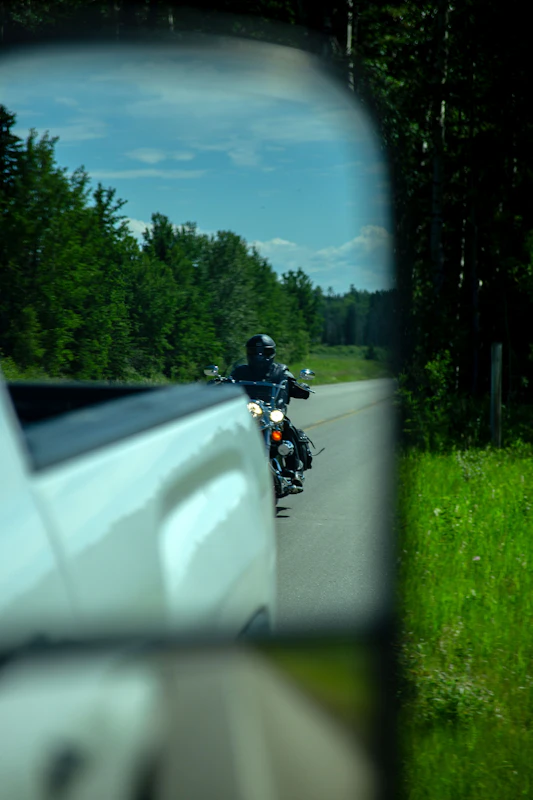 View of motorcycle behind a truck through a car mirror