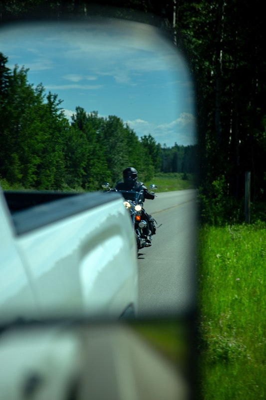 View of motorcycle behind a truck through a car mirror