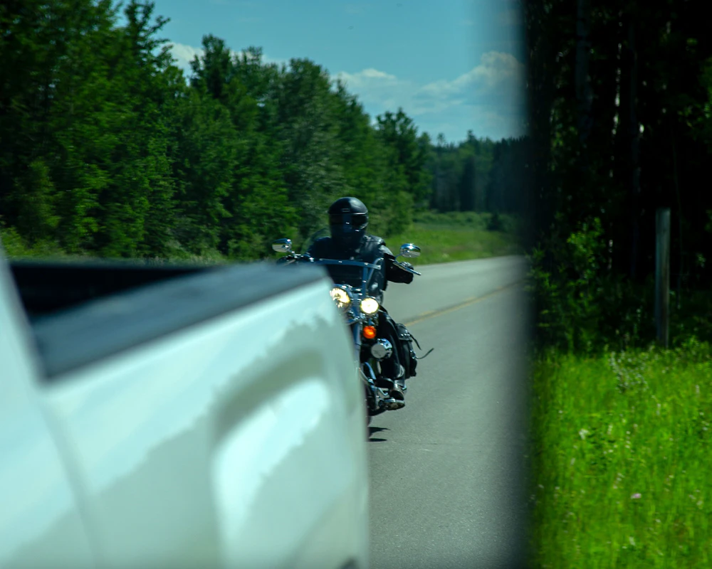 View of motorcycle behind a truck through a car mirror