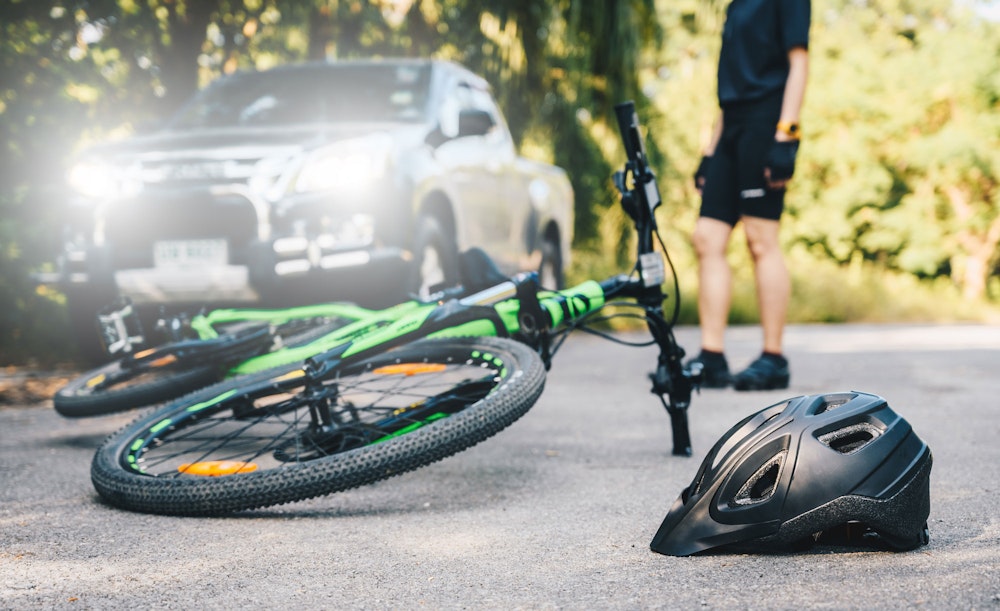 Bike and helmet on the ground with cyclist standing in the brackground