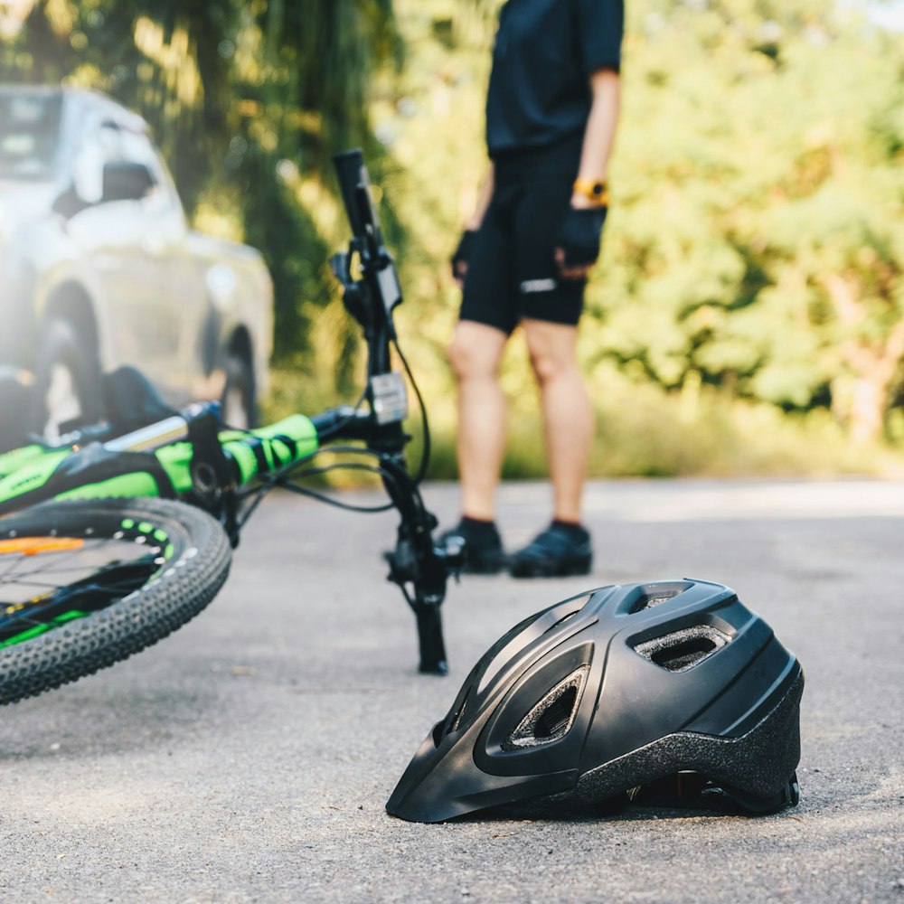 Bike and helmet on the ground with cyclist standing in the brackground