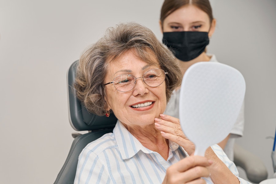 senior woman smiling in a handheld mirror