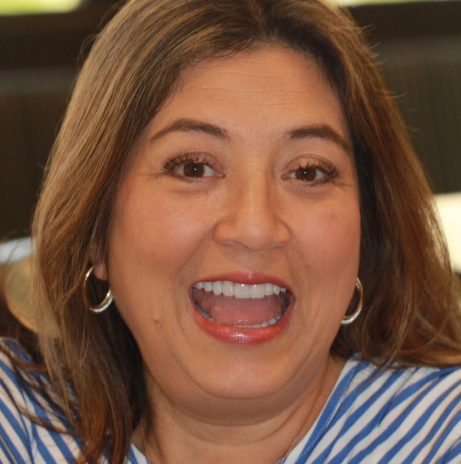 Smiling woman with long brown hair and hoop earrings wearing a blue-and-white striped shirt