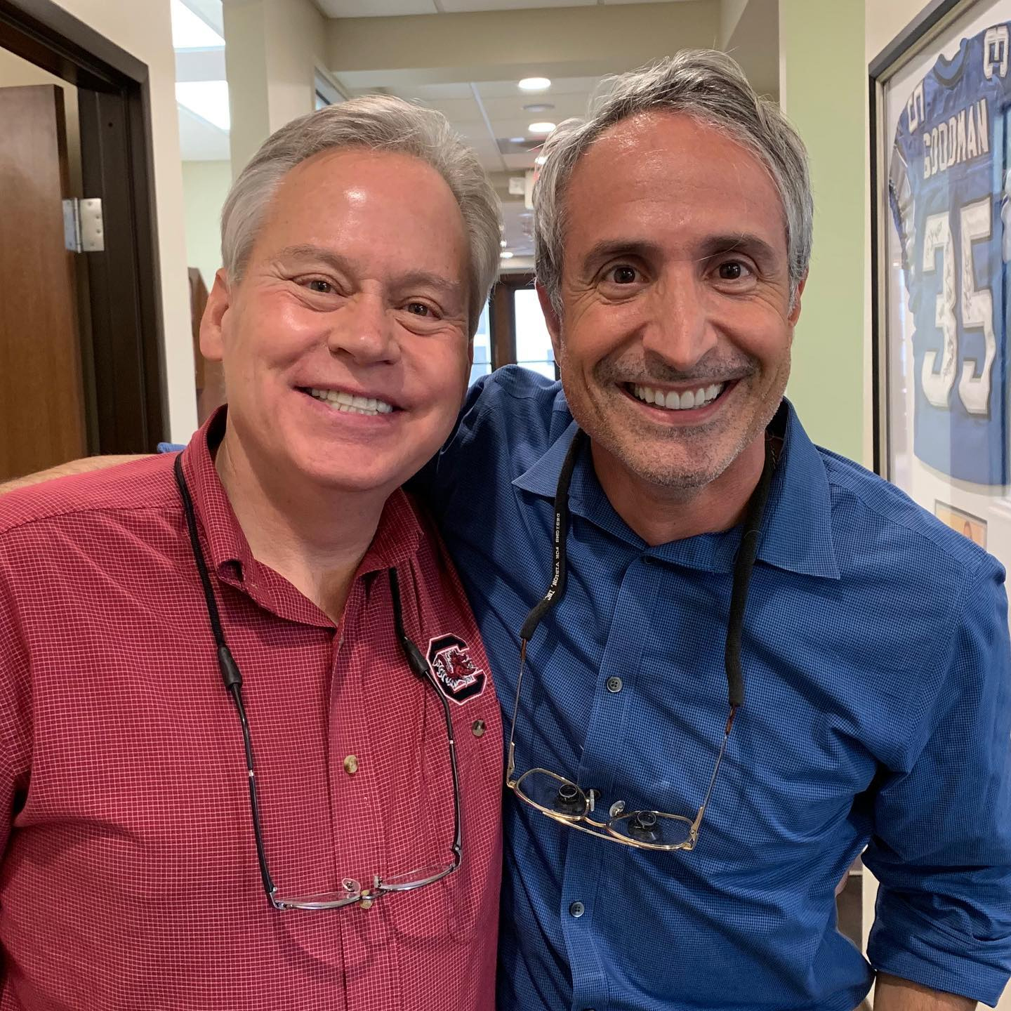 Four women wearing face shields and protective masks, standing in front of a landscape painting in a medical or dental office