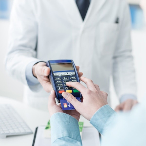 a hand making a payment at a POS machine