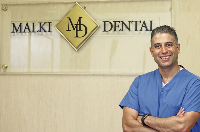 Dr. Malki smiling with practice sign in the background