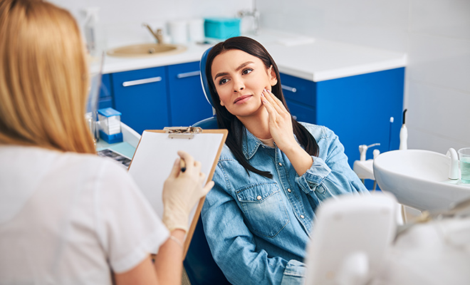 Woman holding jaw during dental appointment
