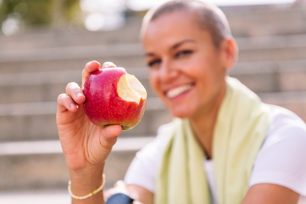 Person holding an apple with a bite taken from it
