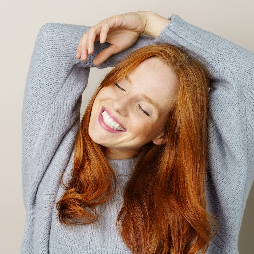 Young woman smiling and reaching arms above head