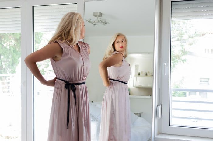 Woman looking at herself in a full-length mirror