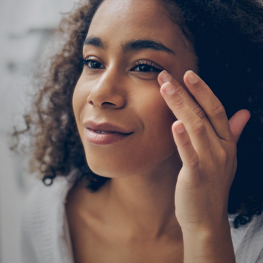Woman looking at her eyes in mirror