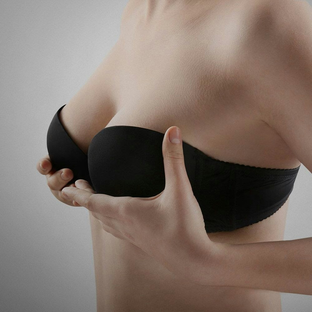 Woman in a black bra, cupping her breasts