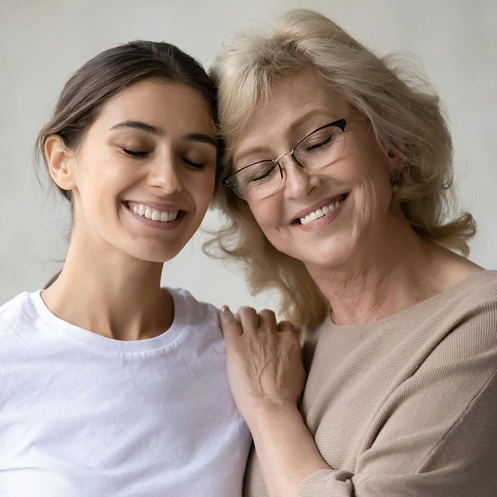Mature woman with new dentures smiling with a younger relative