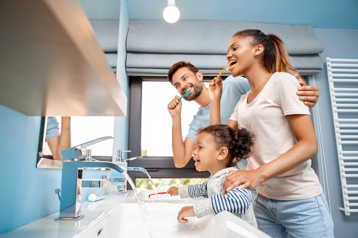 Parents brushing teeth with young daughter