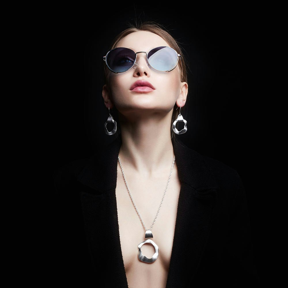 Woman wearing glasses looking up in a black outfit showing cleavage