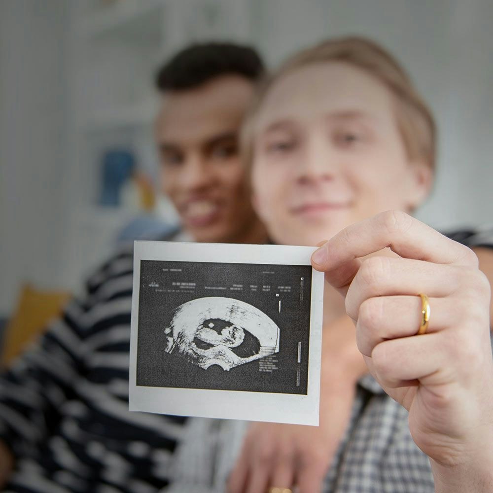 Gay couple showing ultrasound of baby