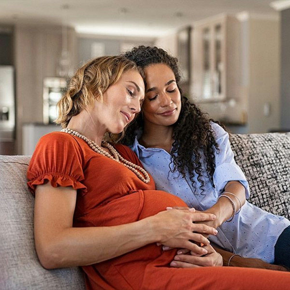Woman pregnant with other woman holding her