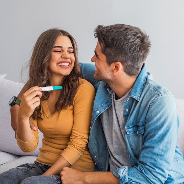 Man and woman smiling over a pregnancy test