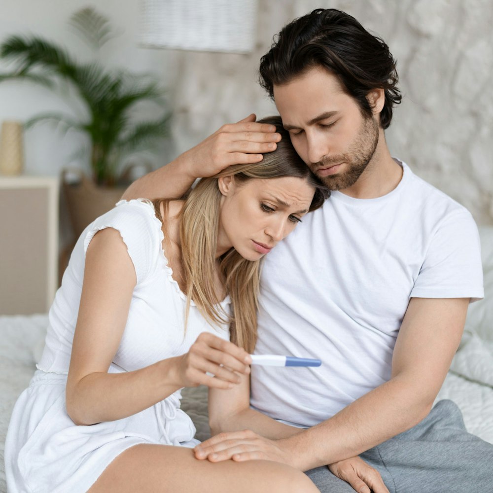 Sad woman with her partner looking at a pregnancy test