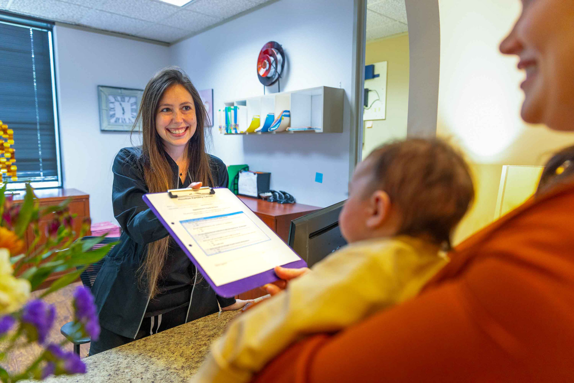 Smiling front staff handing patient paperwork